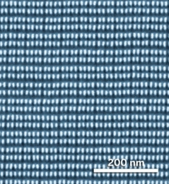 By etching polymethyl methacrylate from a self-assembled polystyrene-PMMA film, researchers created a nanoscale polstyrene line pattern (SEM at bottom) and used it to make a template for patterning computer hard disks (top). Packed in at 1.6 trillion dots per sq in, the white features are raised pillars, with tops measuring just 8 × 13 nm. Credit: HGST/San Jose